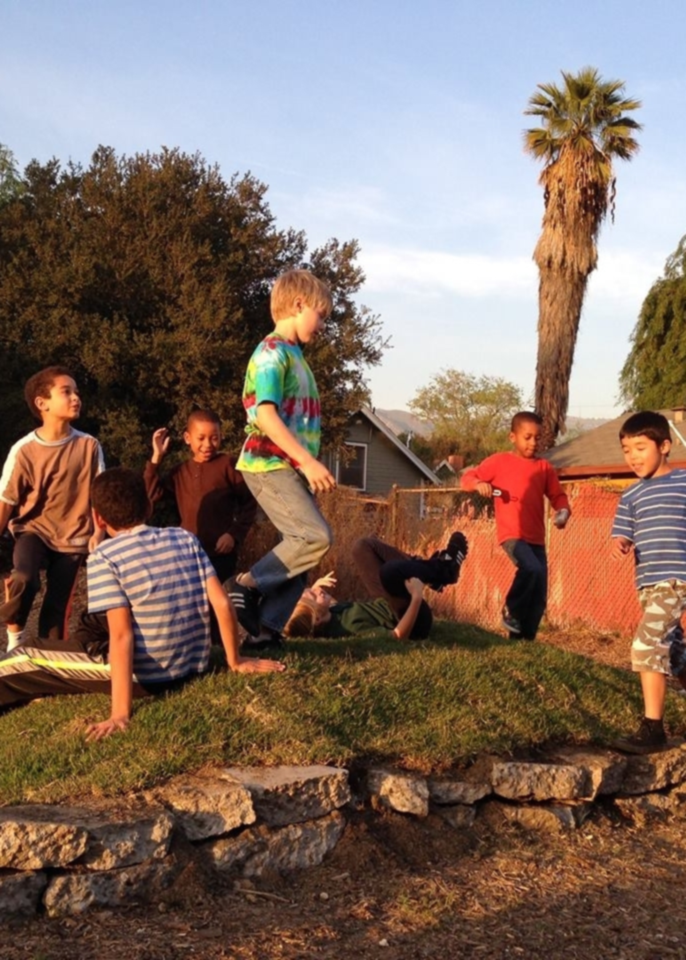 Children playing together outdoors on a grassy mound